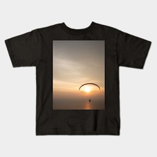 Paragliding over the ocean while golden sunset Kids T-Shirt